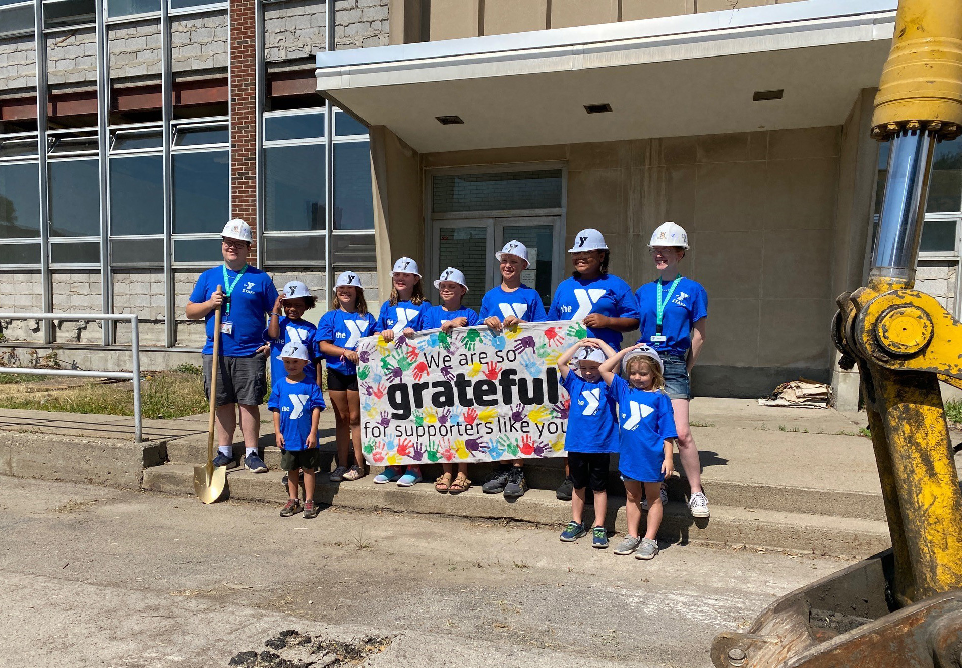 Image of children in hard hats holding a sign that says "We are so grateful for supporters like you"