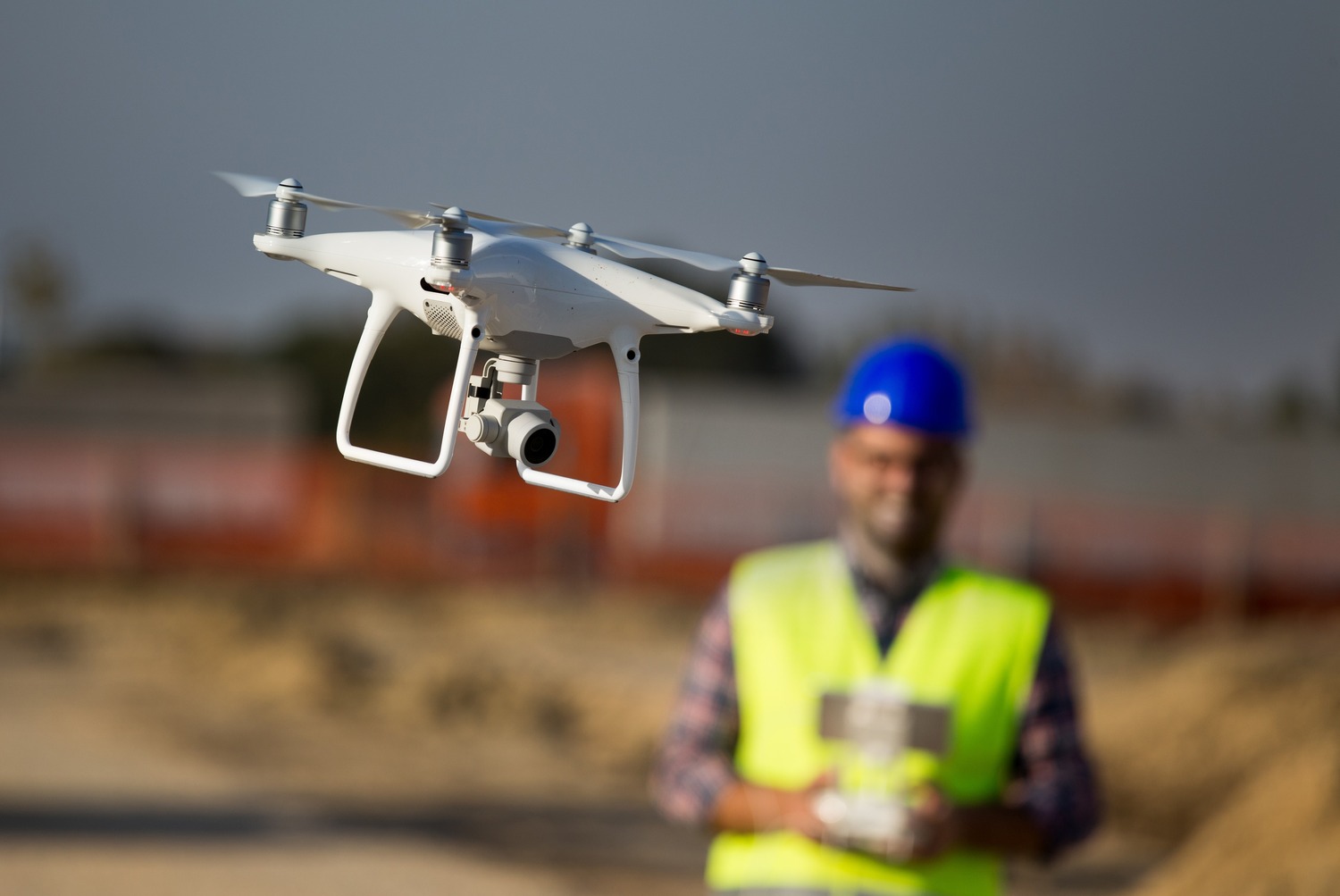 Man in construction hat flying a drone
