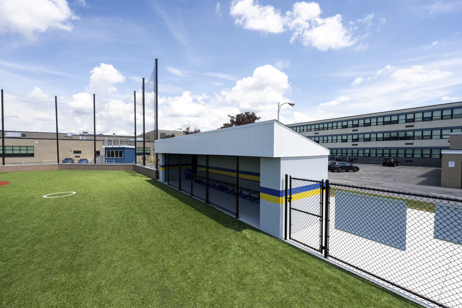 Sleek exterior of the dugout, a concrete structure with a blue and yellow stripe.