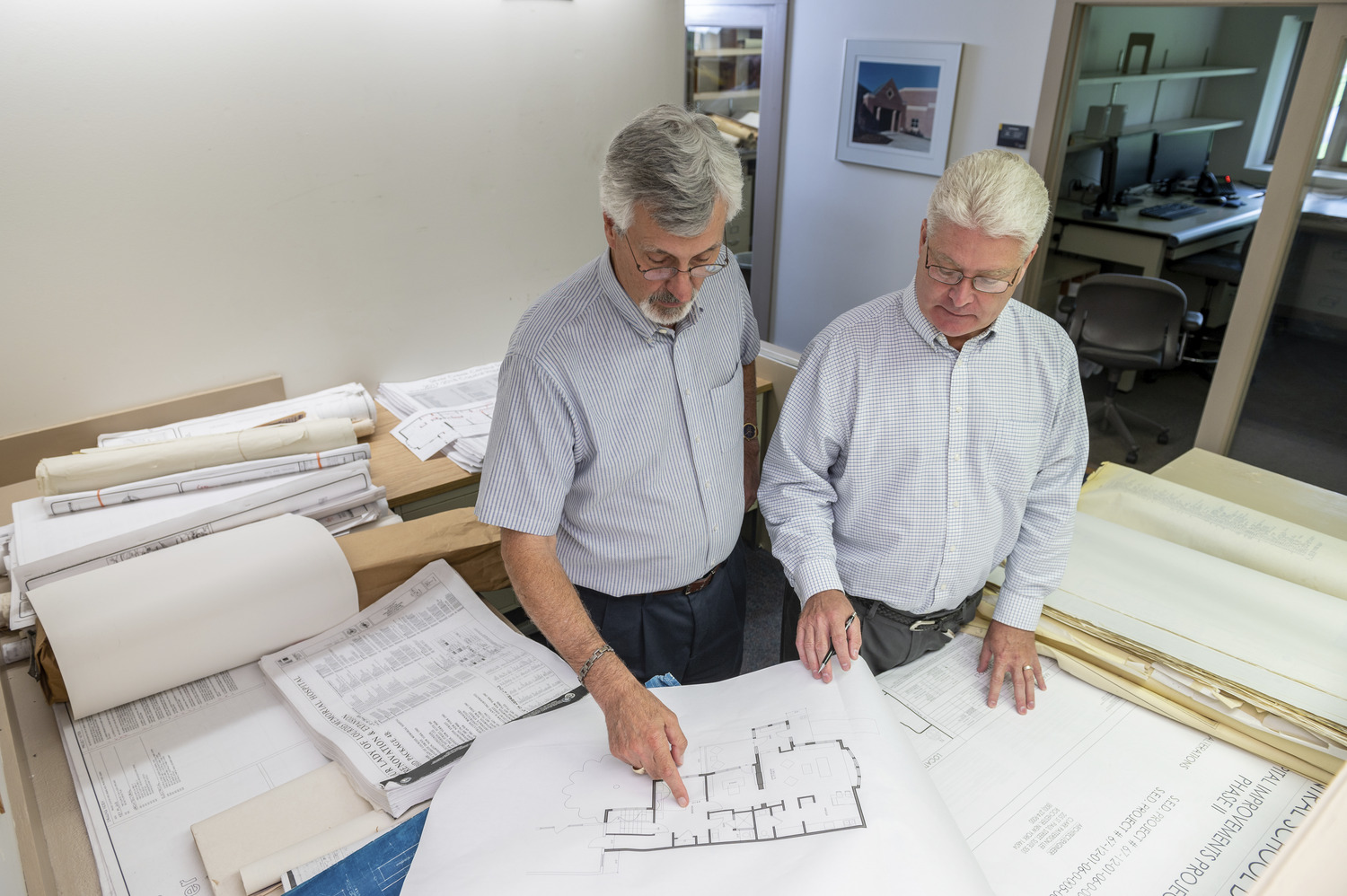 Two men study blueprints together.