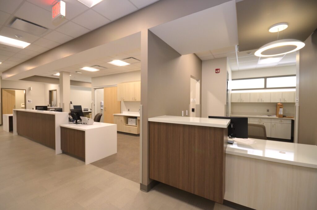 A hallway, row of brightly lit working areas with desks.