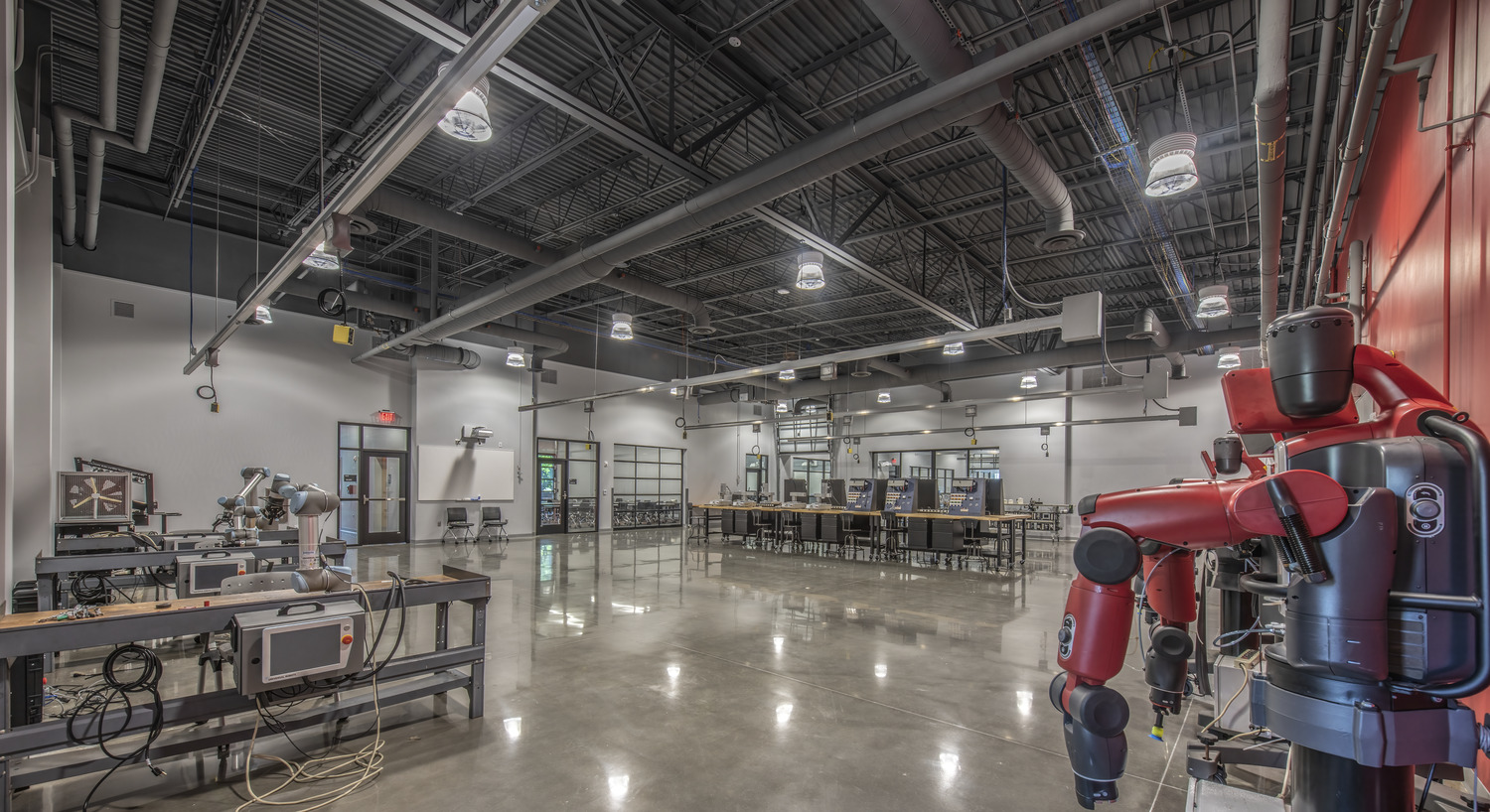 Image shows the Center for Advanced Manufacturing and Emerging Technologies (CAMET) at Chattahoochee Technical College. Image shows a classroom/lab space that has tables for students and has a very industrial look and feel. 