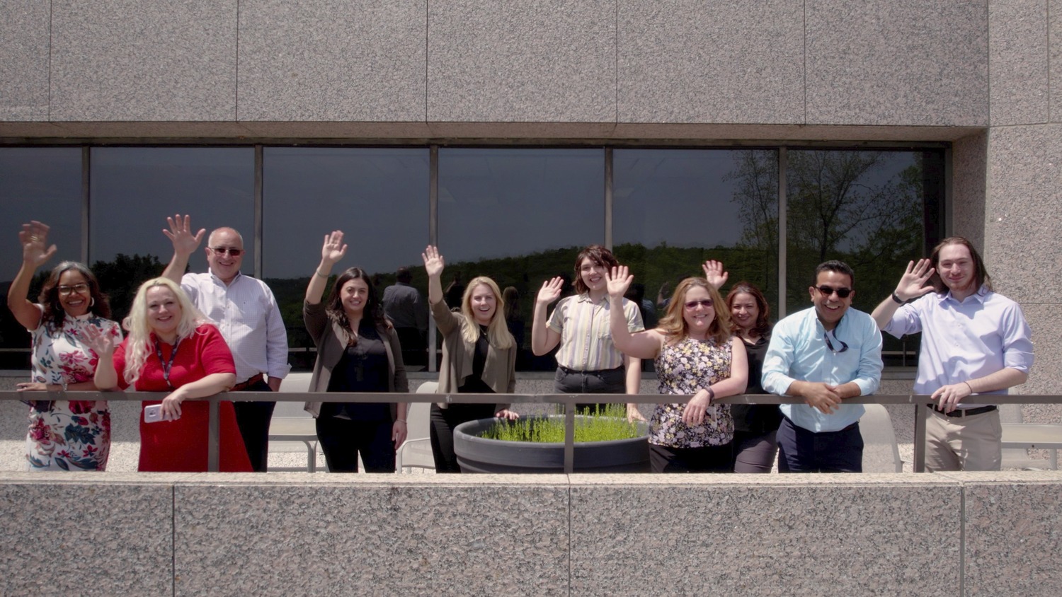 Image shows the people of the CPL Westchester office. They are all standing outside and waving towards the camera.