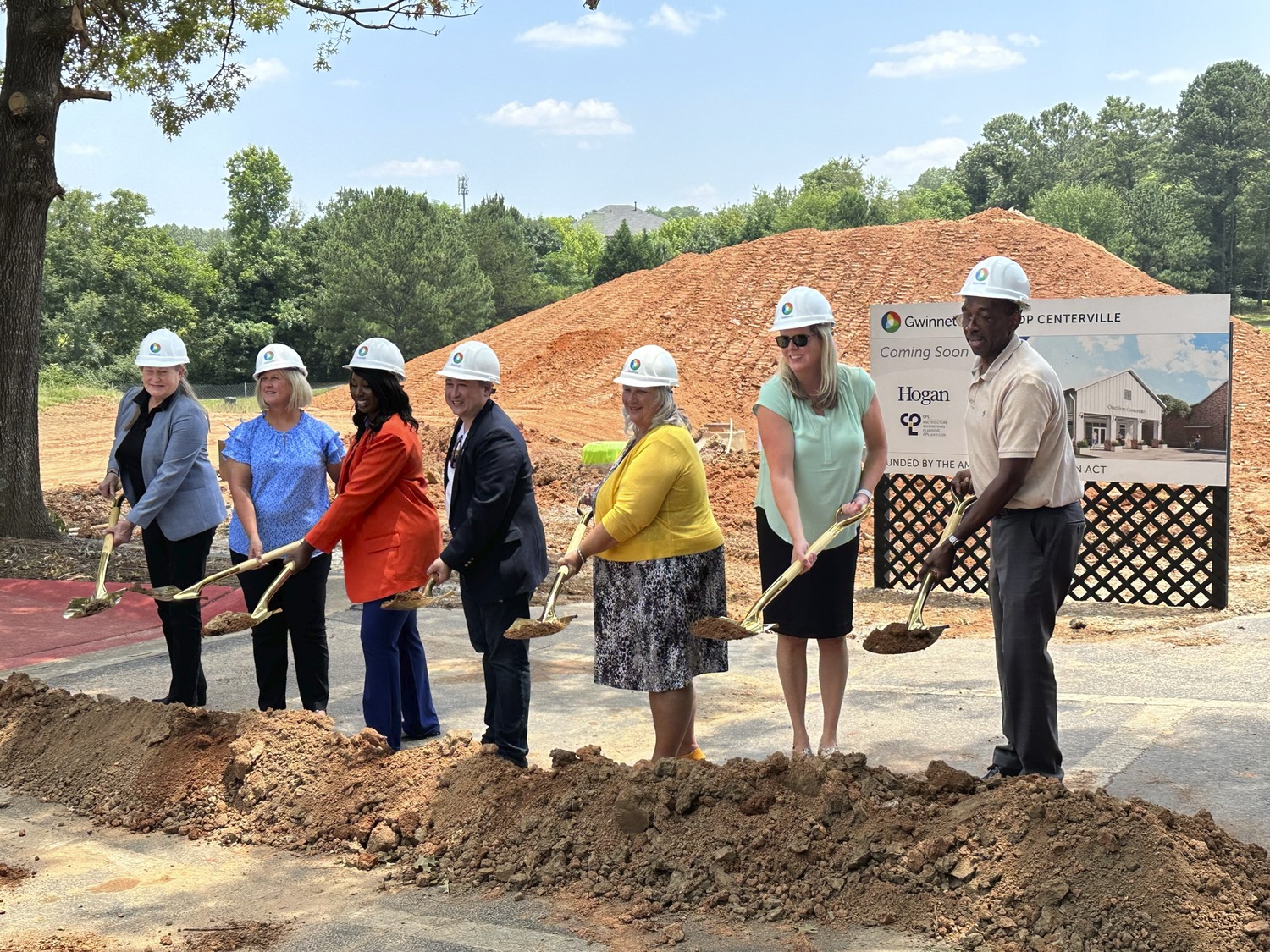 Image shows 7 people wearing hard hats and holding shovels of dirt at the ground breaking ceremony for the Gwinnett County - OneStop Centerville Community Center