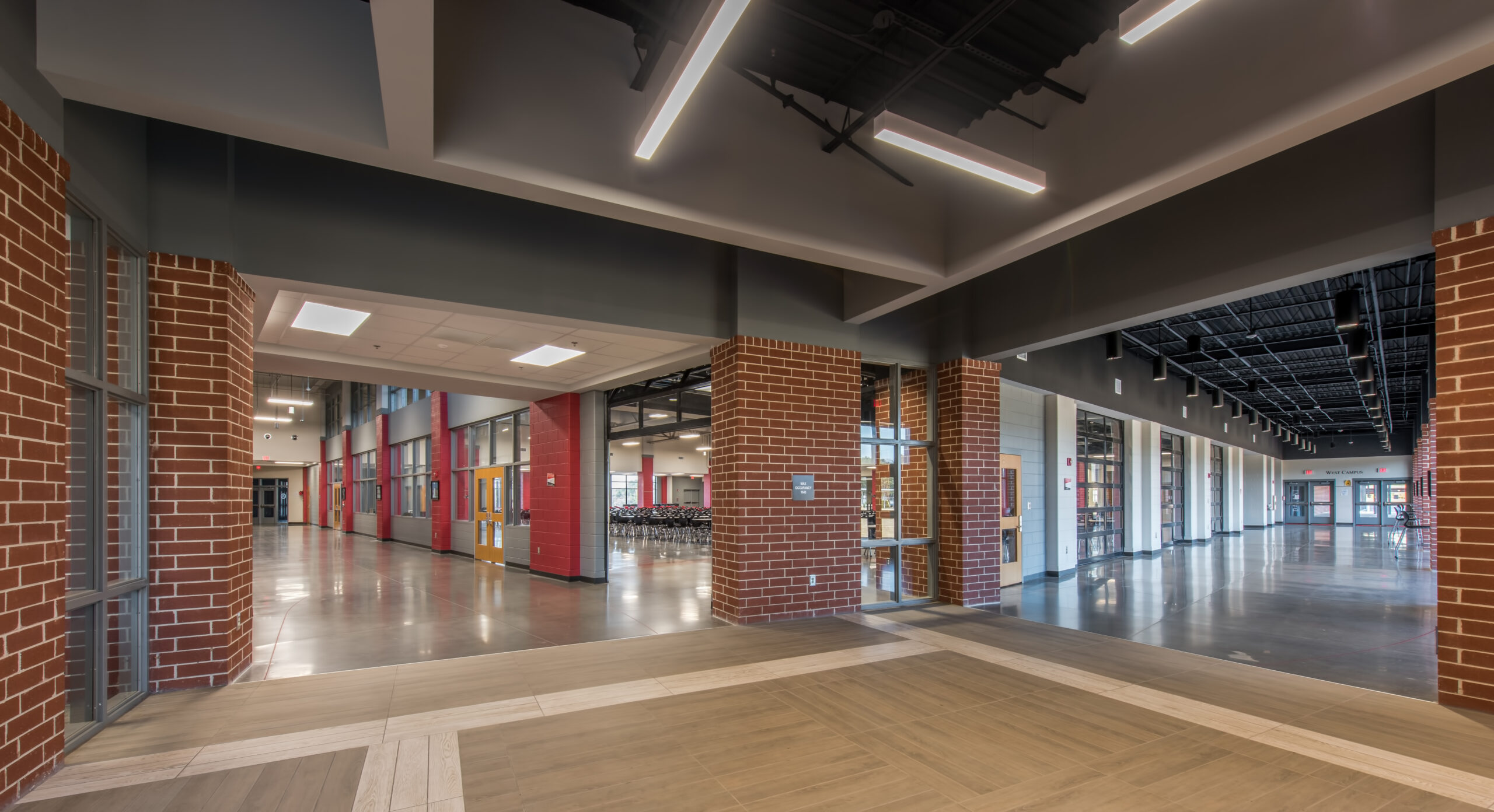 High school hallway with brick walls and red accents with view into classroom