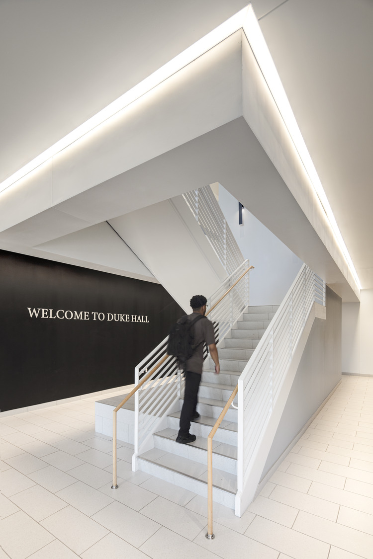White stairs with a person walking up them. The far wall reads "Welcome to Duke Hall"