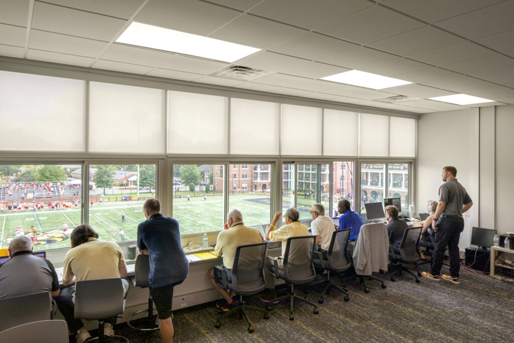 A VIP event suite at Randolph Macon college. There are spectators watching the field below from a window.
