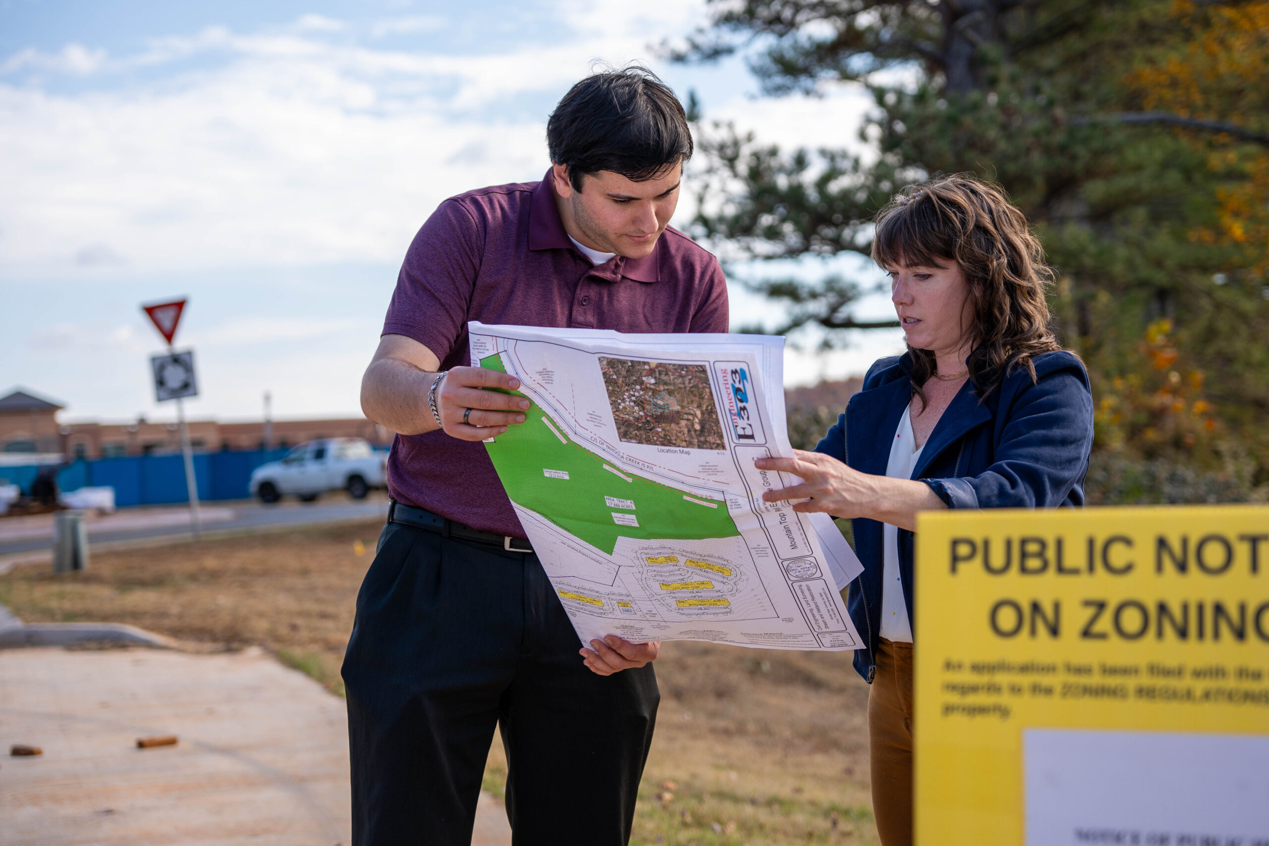 Man and woman examine municipal zoning plans next to a sign about zoning