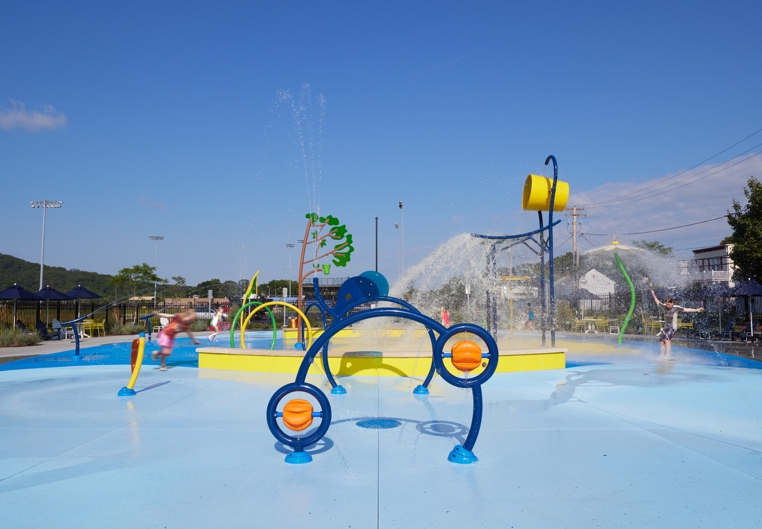 Splash park water features including pouring buckets and spraying flowers and trees at the Delano-Hitch Aquatic Center with Pool and Splash Park