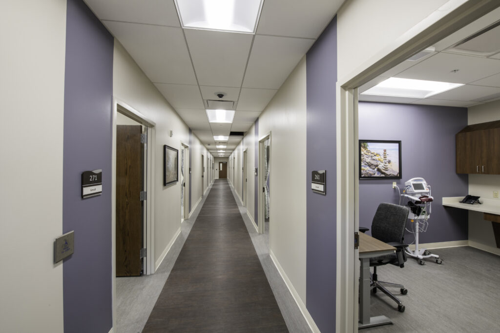 MPA_2021_001_N12 copy Veteran Affairs Community Outreach Clinic hallway with carious offices and patient rooms with dark wood floors and purple walls