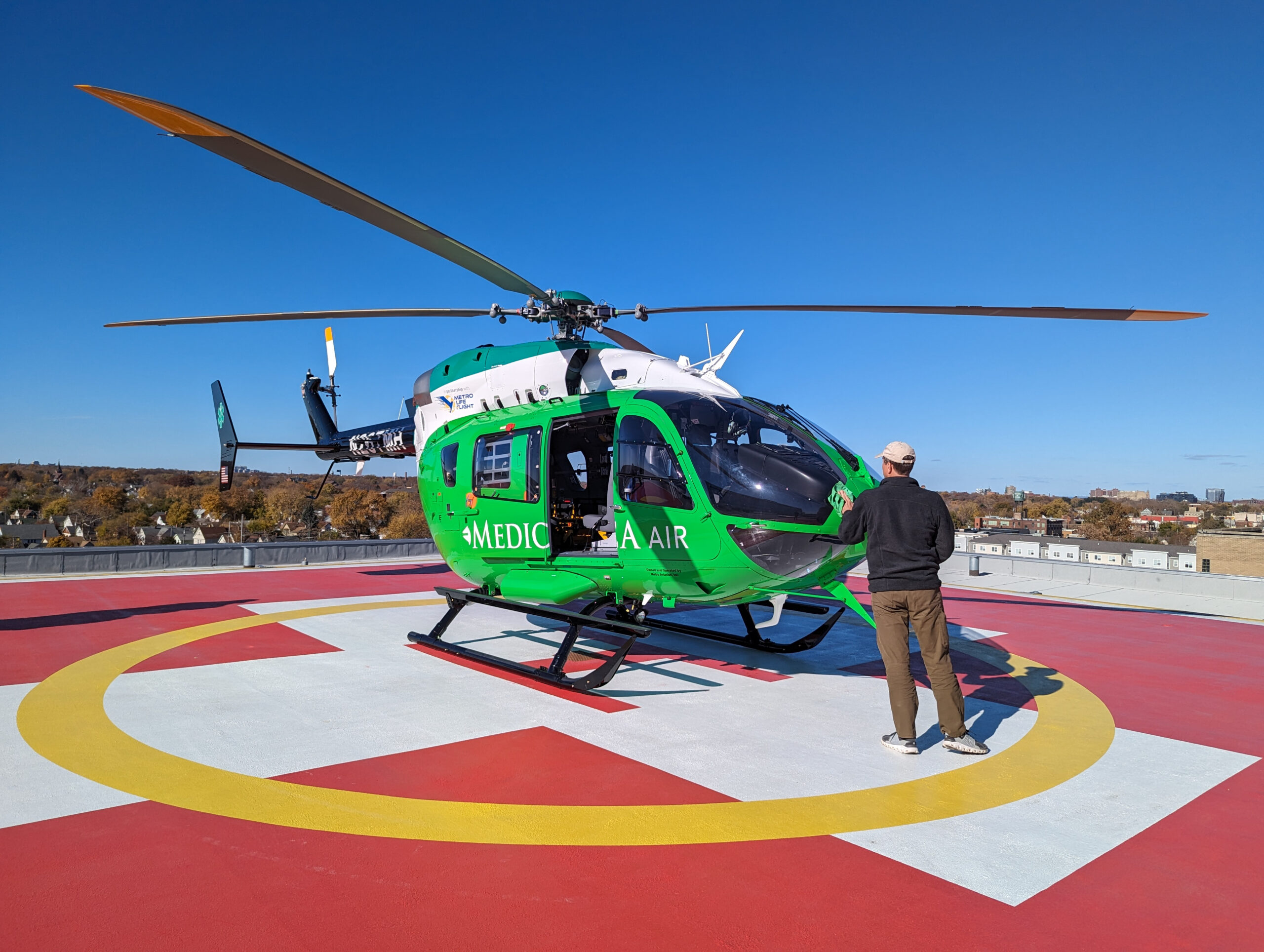MPA_2022_002_MetroHealth_CCP_N2 MetroHealth Critical Care helipad - green helicopter on red and yellow helipad with man standing next to it