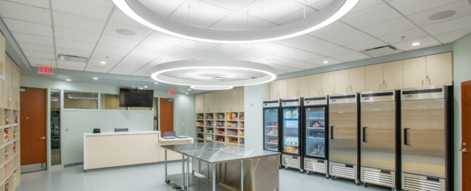 A food pantry with freezers on one side, tables in the center, and a register style table on the far wall.