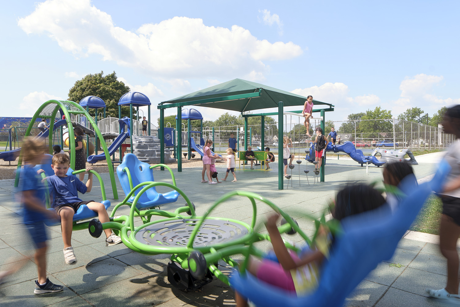 Children play on an adaptive elementary school playground with tactile features and other interactive elements that promote inclusivity. 