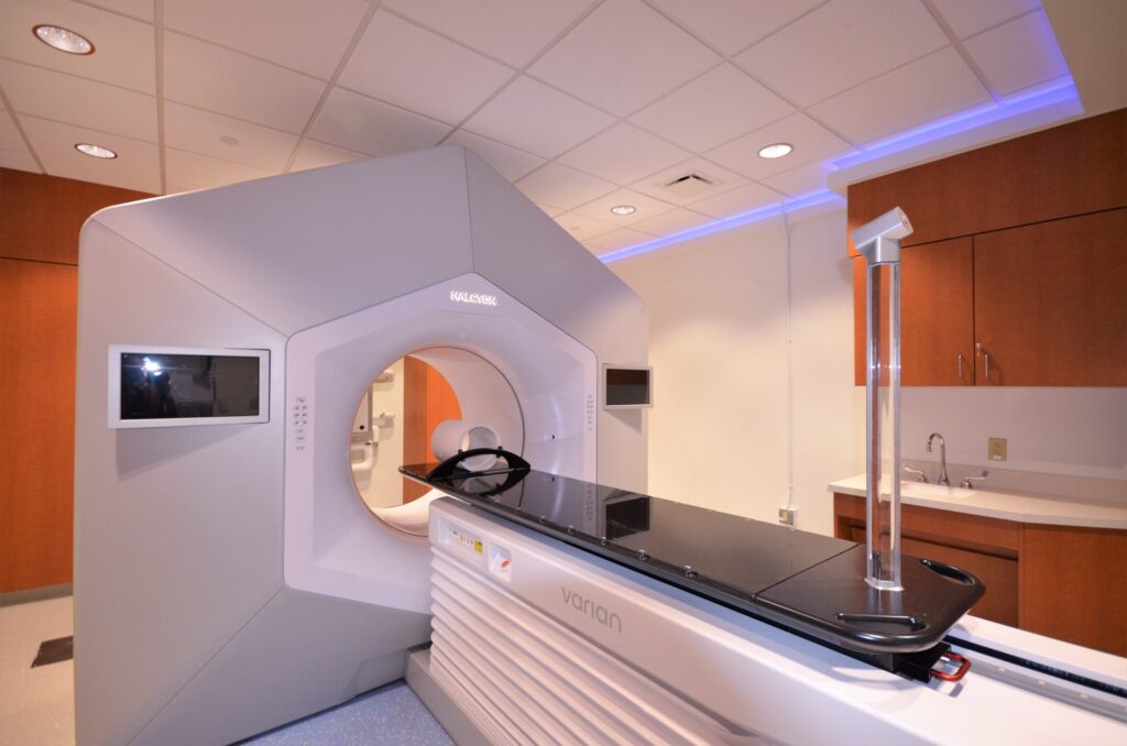 Another view of the linear accelerator and slab, in a room with wooden cabinets and with calming lighting.