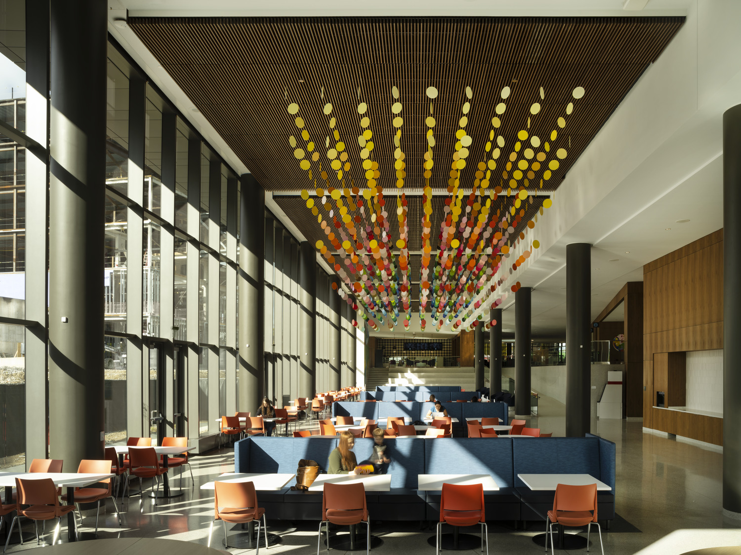 MetroHealth Glick Center cafe area with seating, columns, tall windows and colorful circle decorations hanging from the ceiling.