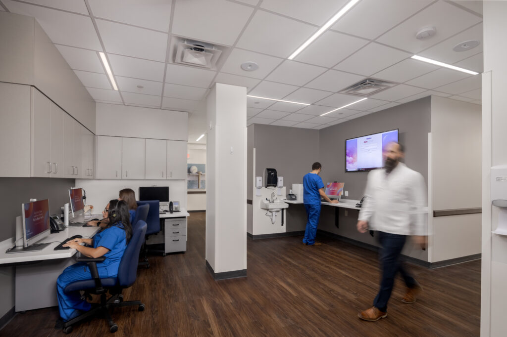 Busy nurses station with doctor walking through as nurses work on computers
