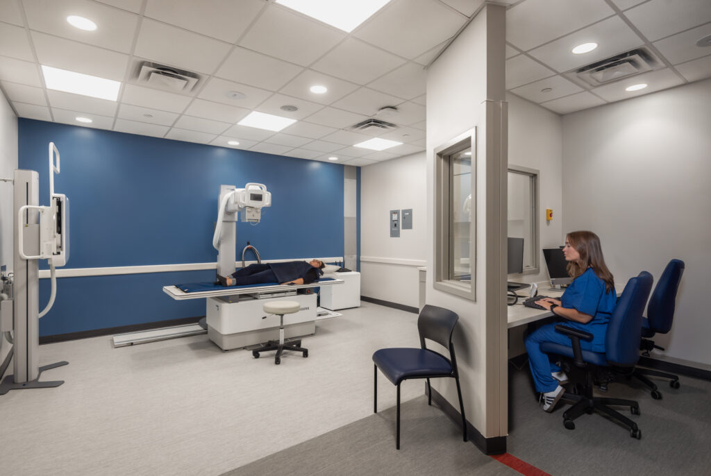 Nurse conducting an xray on a patient in a room with blue walls at Victor Medical Center