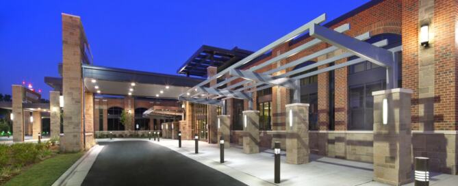 Nighttime view of the Hoke Community Hospital by FirstHealth of the Carolinas, showcasing the facility’s main entrance canopy, brick façade, and illuminated drive-up access.