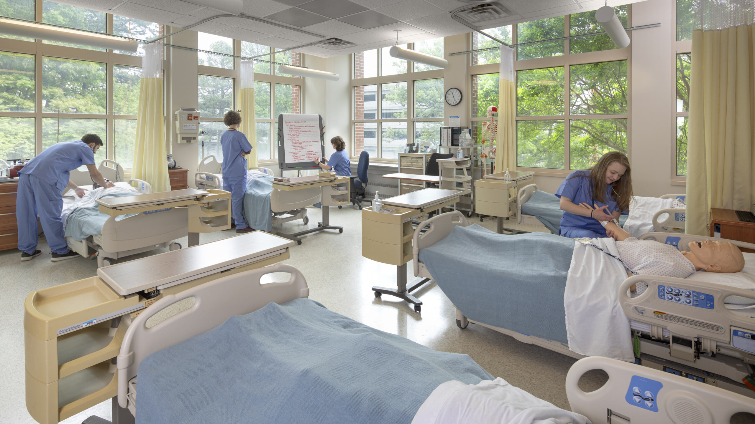Simulation lab at UNC Chapel Hill ITS Manning School of Nursing with various nursing students in scrubs working with manikins