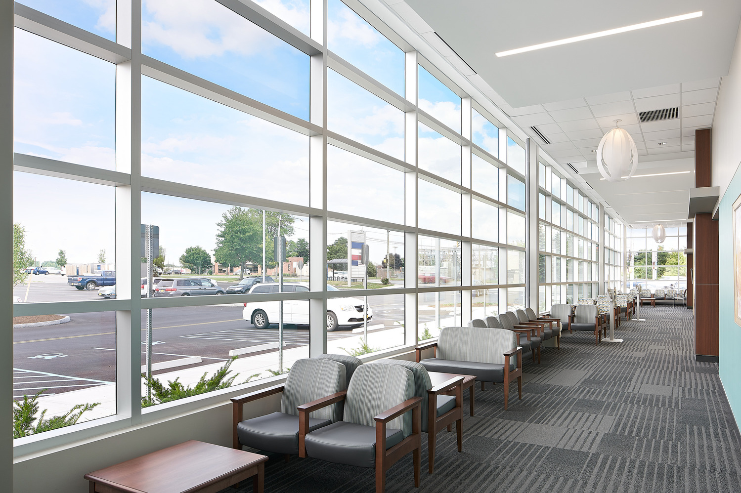 A seating area with rows of chairs alongside a long and narrow wall of windows at the front of Rochester Regional Health.
