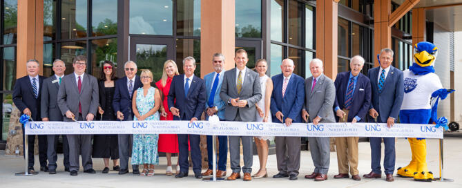 A group of people stands in front of the recently completed David E. Ralston Hall at UNG Blue Ridge, prepared to cut the ceremonial ribbon.