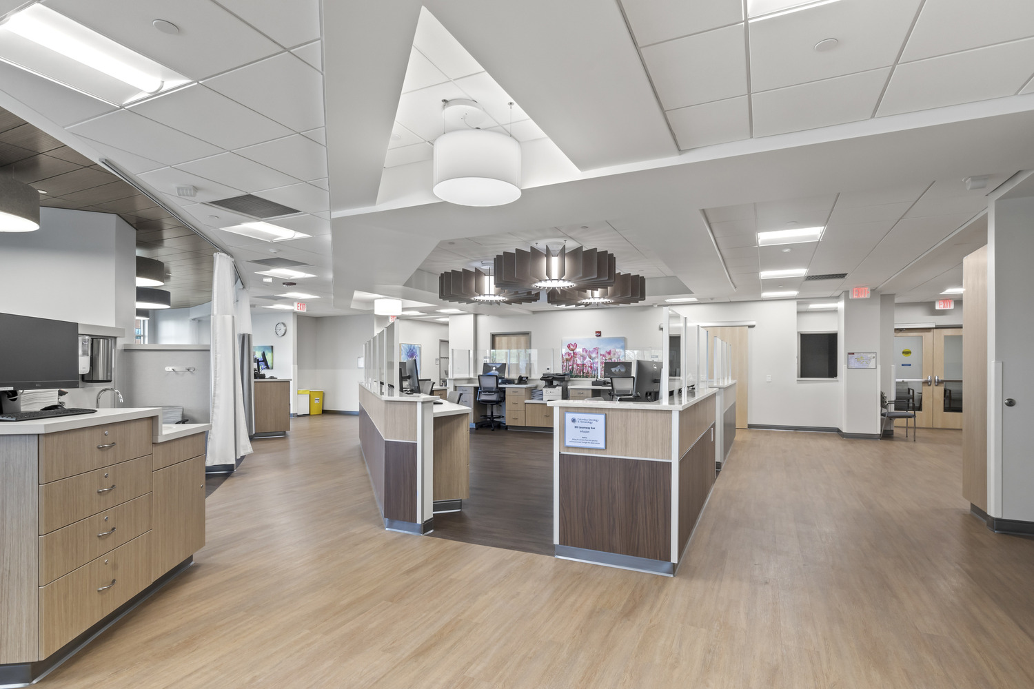 A nurse's station at Westerville Cancer Center has a counter with an entrance, multiple desks, and unique overhead lighting.