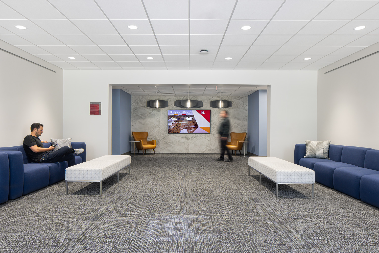 A study space in Bowman Hall with comfortable seating, bright lighting and a monitor with slides.