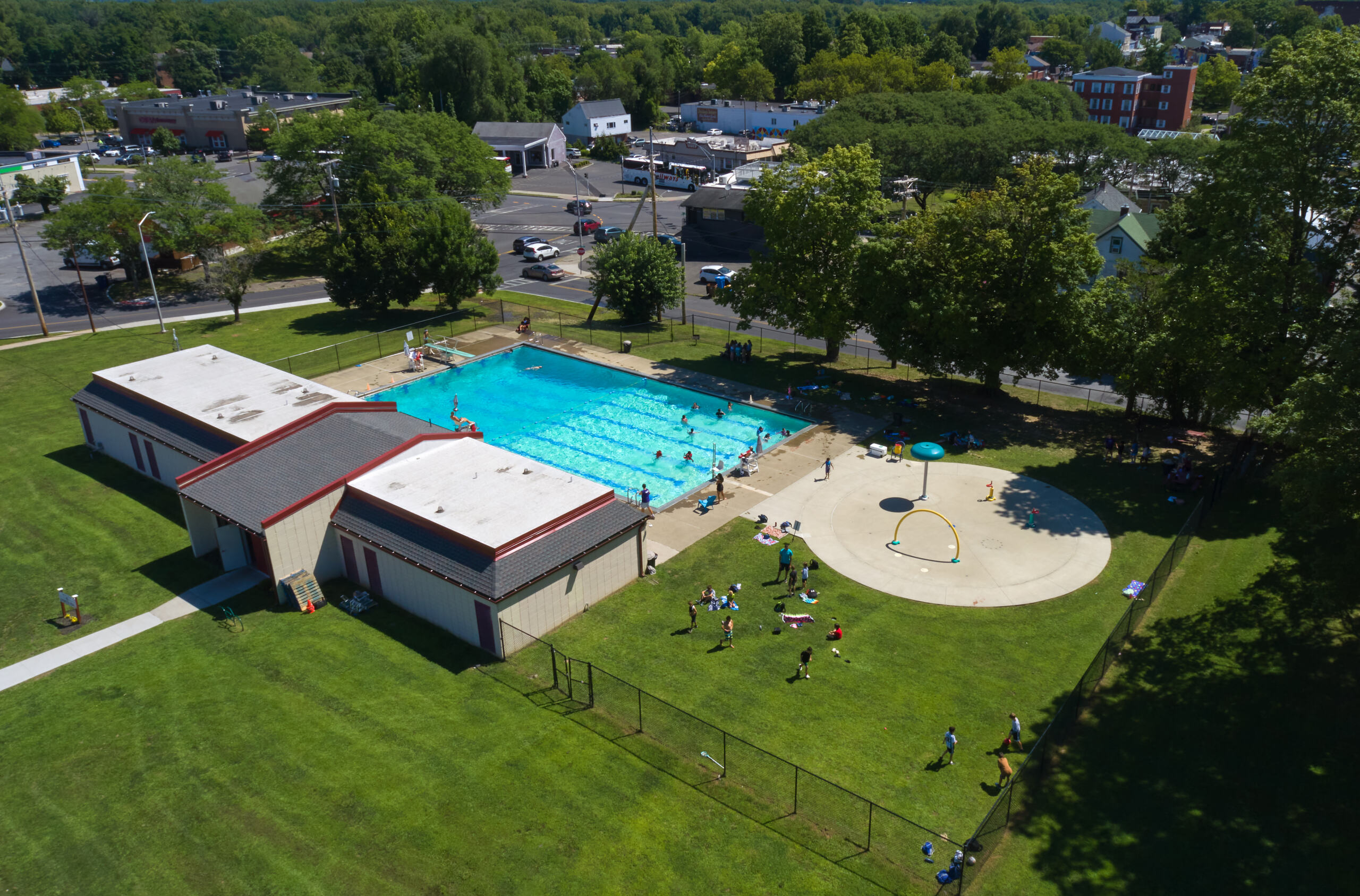 Deitz Stadium Aerial view of the City of Kingston's Dietz Stadium aquatic center, a pool, a splash pad, and children playing in the water and on the lawn.