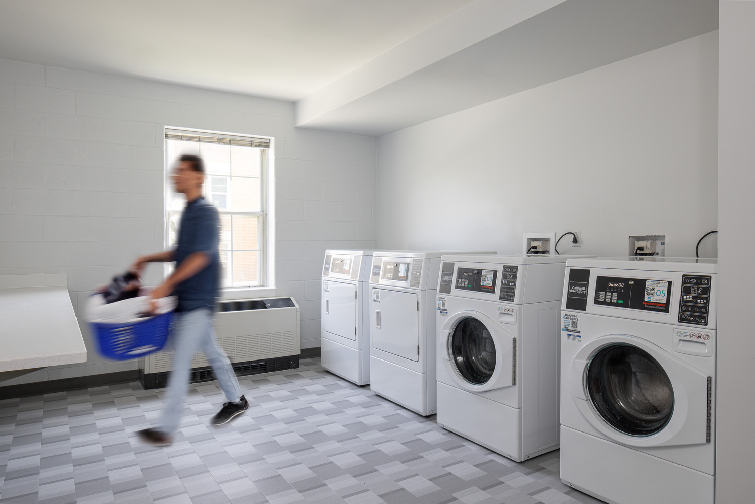 A student carries a basket of clothes in Wakeman Hall's laundry room.