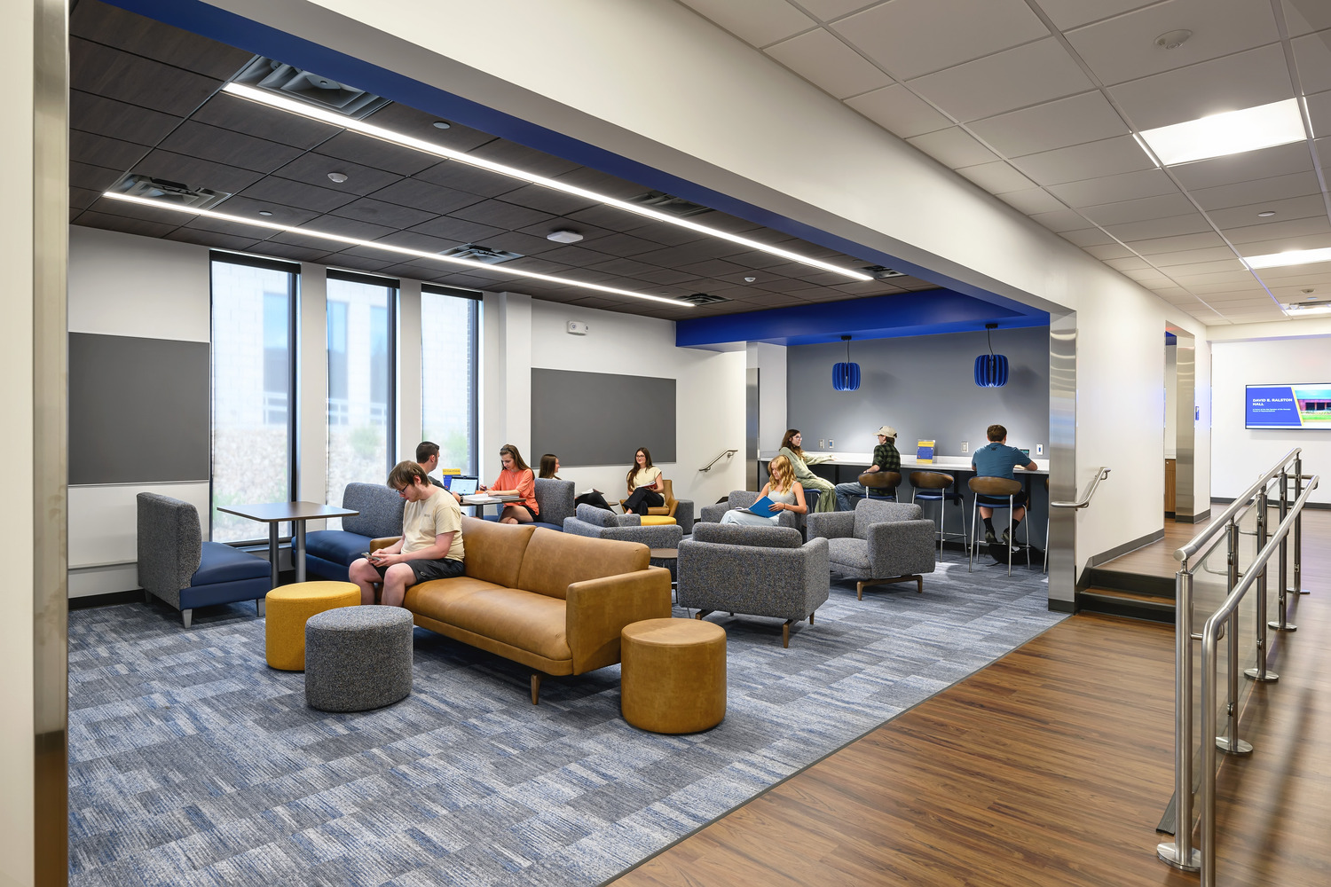 In a breakaway space with patterned carpeting and bright lighting, students sit on chairs, couches and booths to talk, read or work.