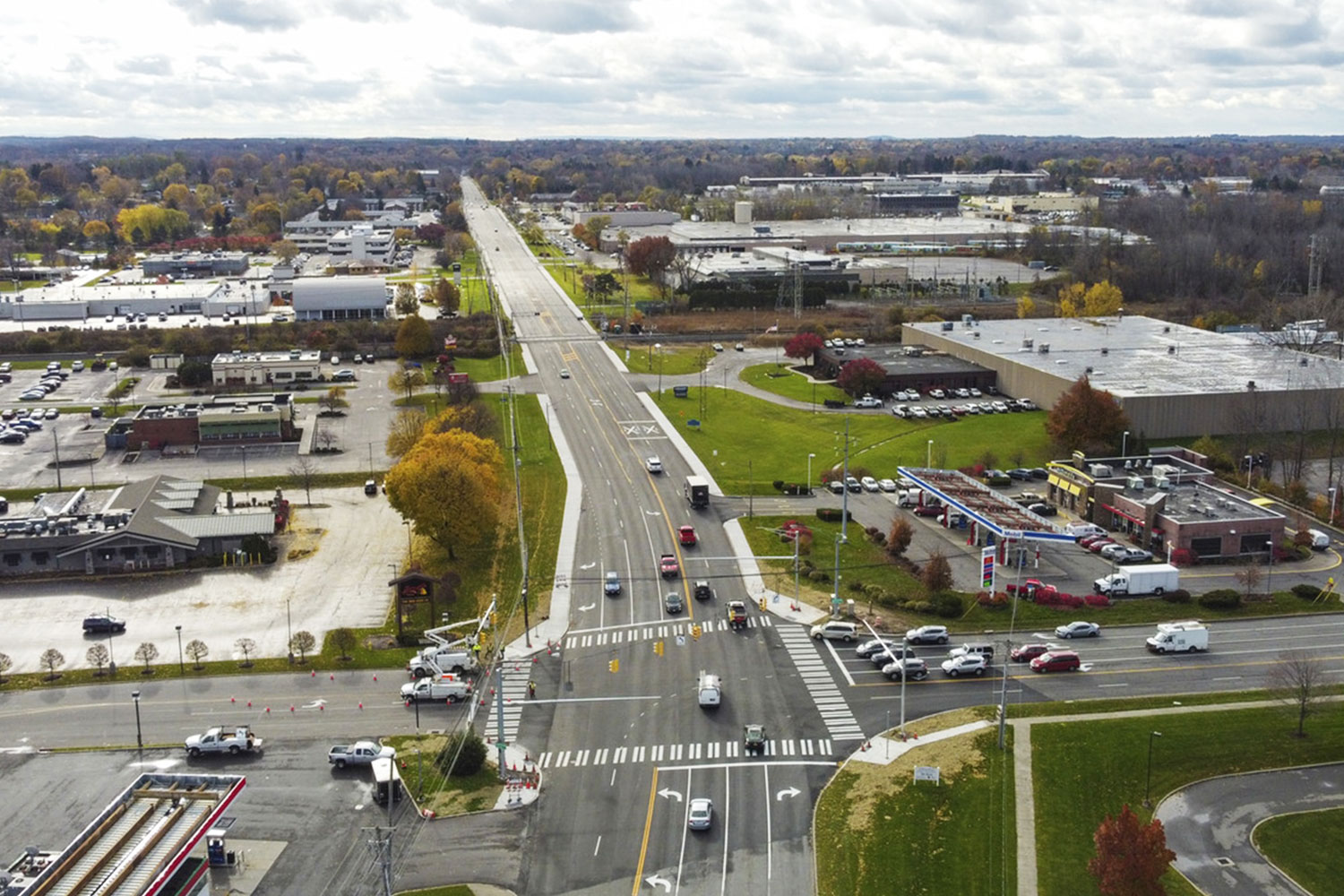 Aerial view of a busy intersection on South Winton Road in a suburban area, surrounded by commercial buildings, parking lots, and autumn trees under a cloudy sky.