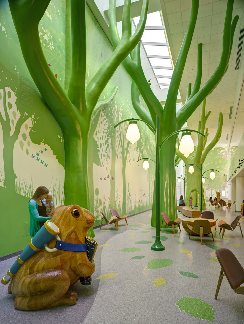 AND_2012_043_N10_medium A colorful play area with tables and chairs, animal statues, lampposts built to look like flowers, and bright green tree sculptures that reach the ceiling. This is at Nationwide Children's Hospital