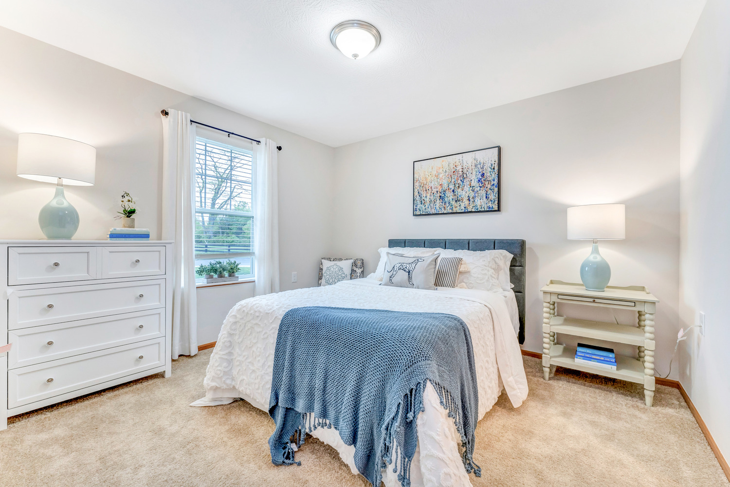 A calming, blue and white bedroom inside a residential unit at Homestead Village Active Senior Living Facility.