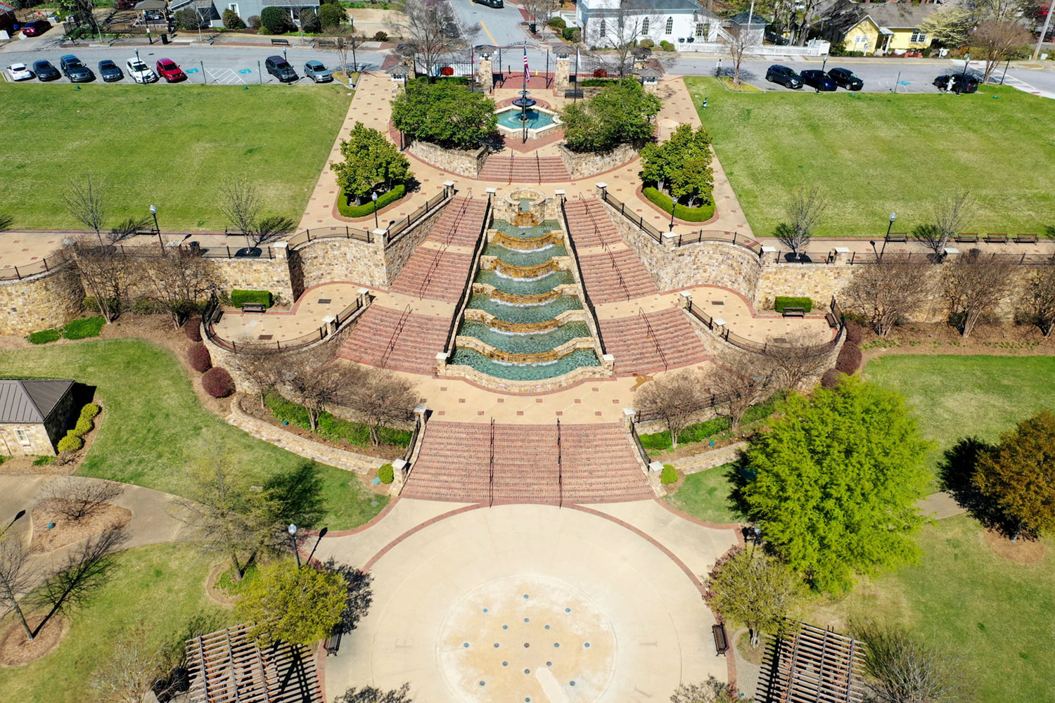 Aerial view of Lillian Webb Field Park showing a tiered fountain cascading down symmetrical stone steps in a park. Surrounded by greenery and pathways, the setting feels inviting.