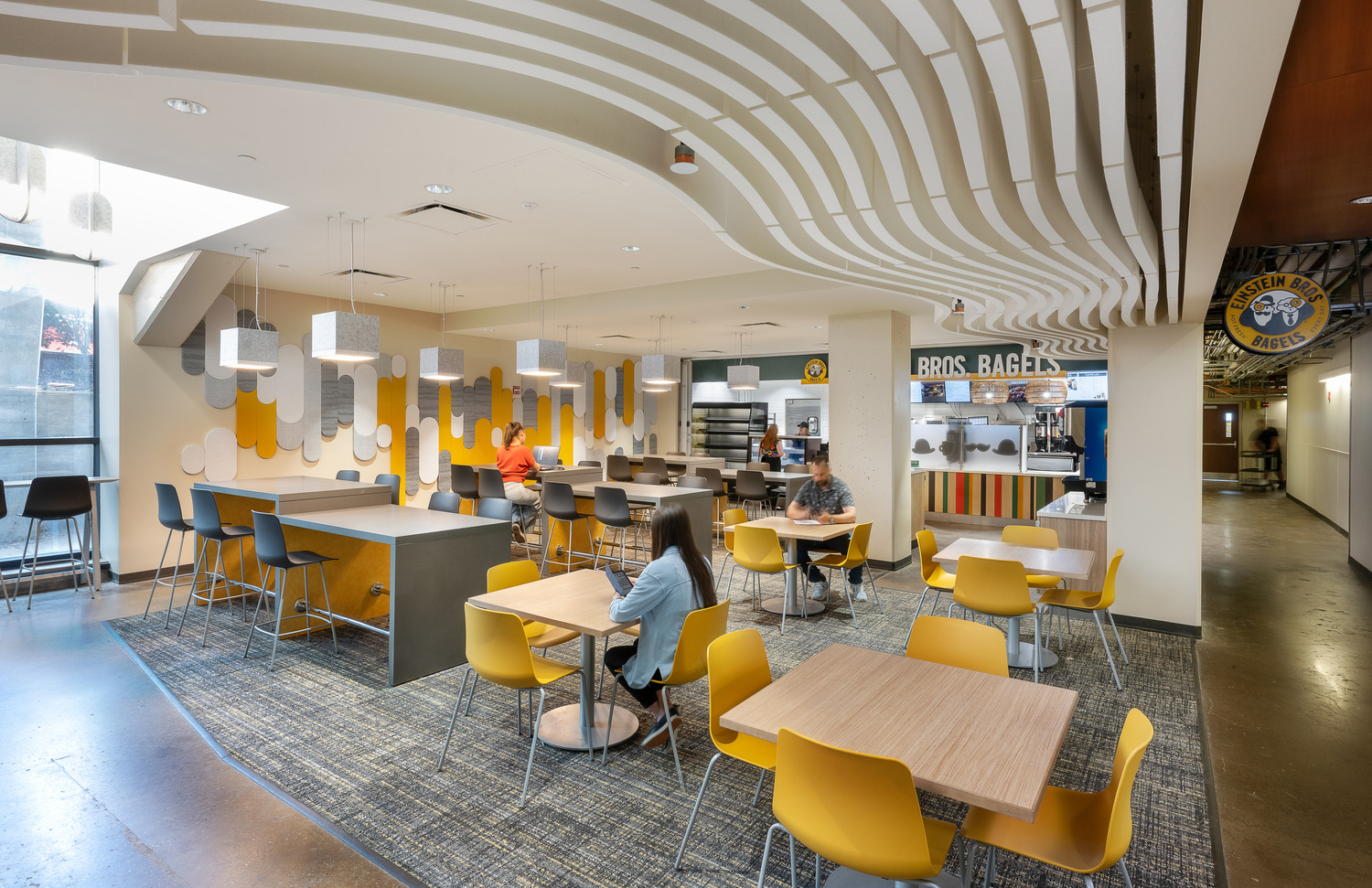 University of Pittsburgh – Einstein Bros Bagel Renovation at Benedum Hall Einstein Bros Bagels' seating area inside Benedum Hall, a colorful and comfortable breakaway space where students sit at tables and counters.