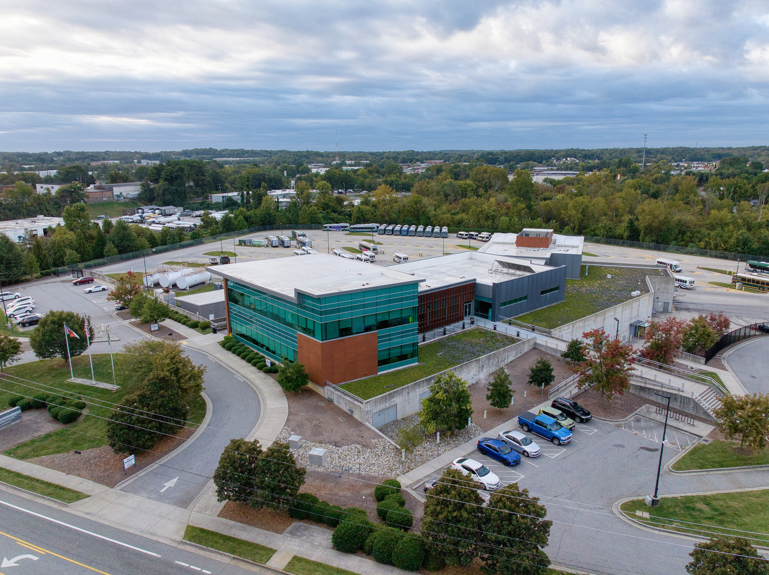 Aerial view of the Greensboro Transit Authority Headquarters , an elevated concrete-and-terracotta building with walls of teal windows.