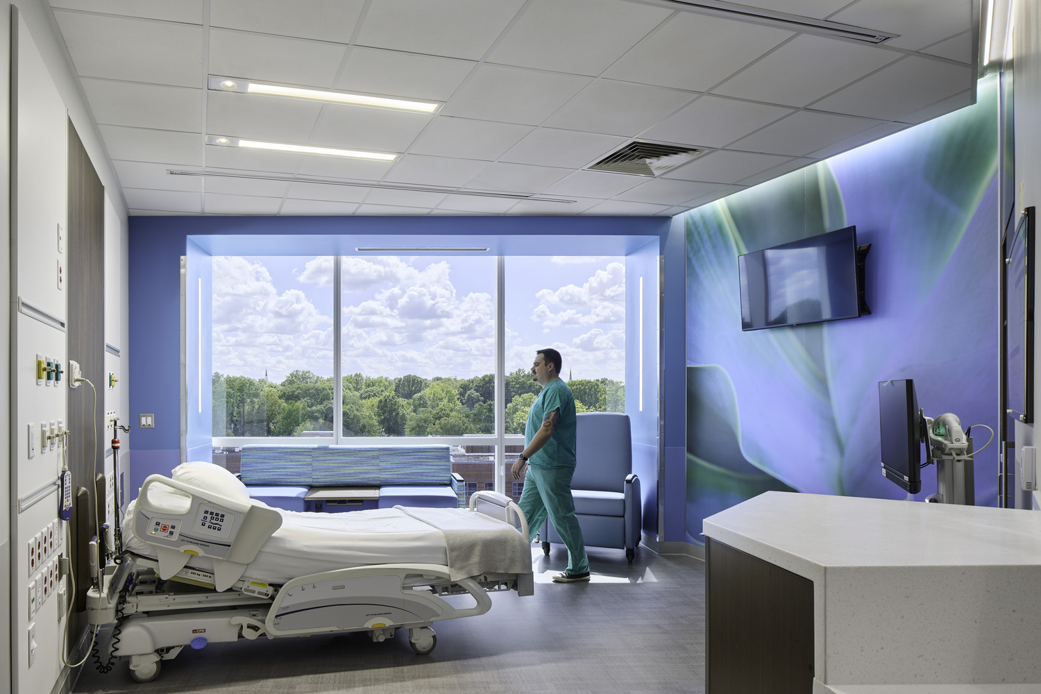 Brightly-lit patient room in Atrium Health Wake Forest Baptist Outpatient Surgery, with male medical professional