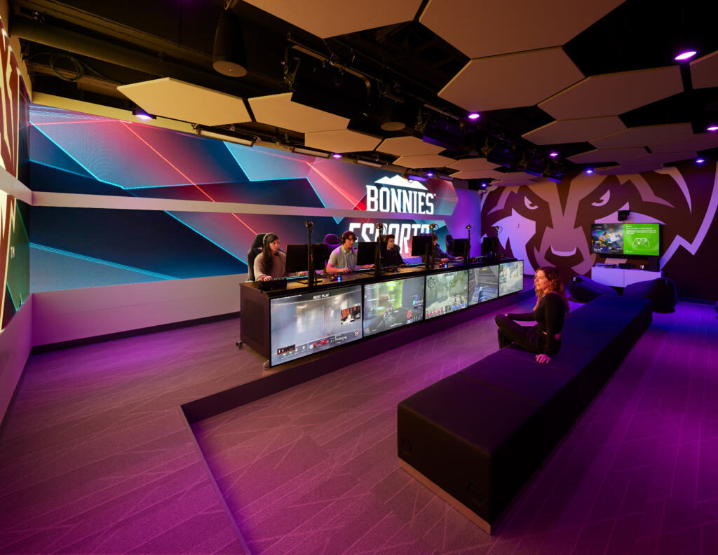 The St. Bonaventure University ESports Suite's row of students at gaming computers. State-of-the-art university esports arena with professional PC gaming stations, spectator seating, immersive LED displays, and team competition setup.
