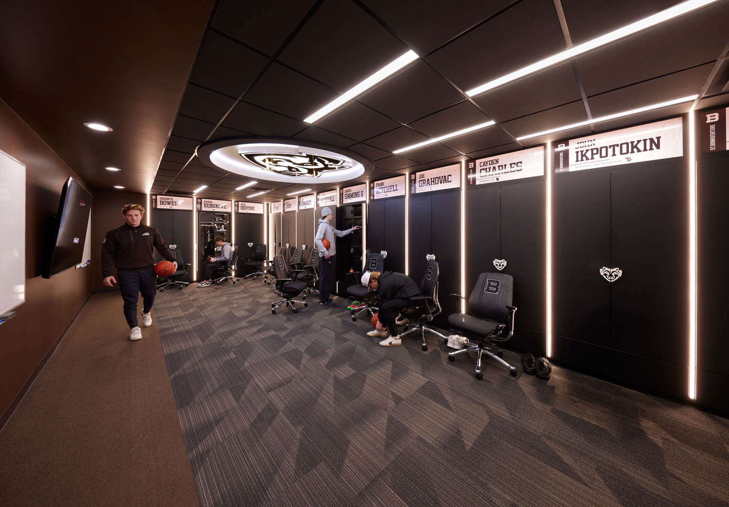 Tall lockers labeled with athletes' names and separated by bright LED strips inside the Men's Basketball Locker Room at St. Bonaventure University.