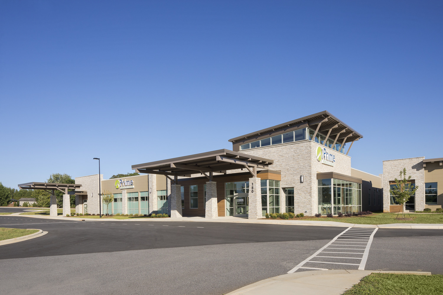 Modern healthcare building with a welcoming entrance and large windows under a clear blue sky. The setting is clean and professional at Rivercrest Ambulatory Surgery Center.