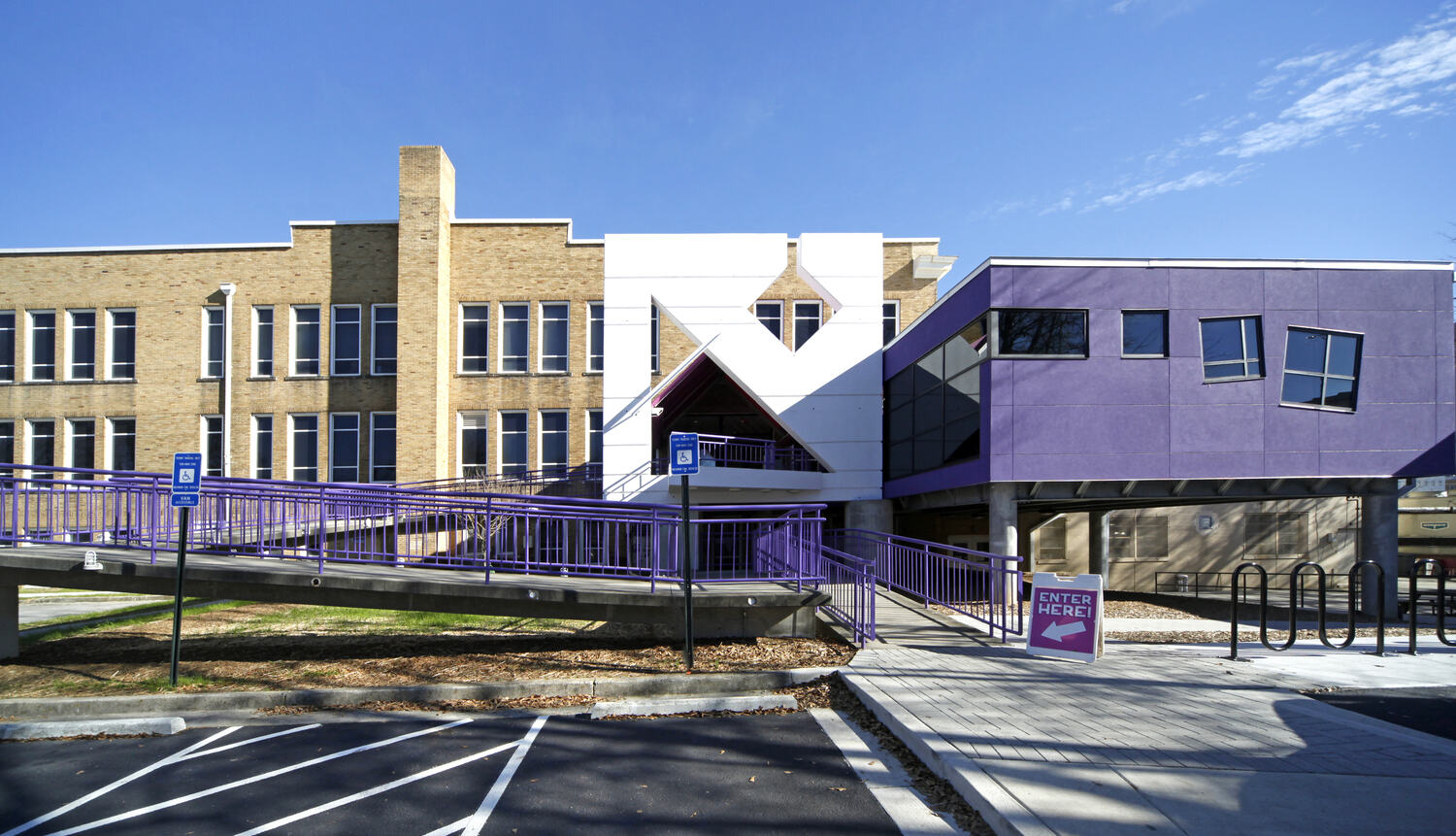 12882_00_Center_for_Puppetry_Arts_N12_medium The modern Center for Puppetry Arts building with tan bricks features purple accents and angular architecture. A purple ramp and bright blue sky add a vibrant, welcoming feel.