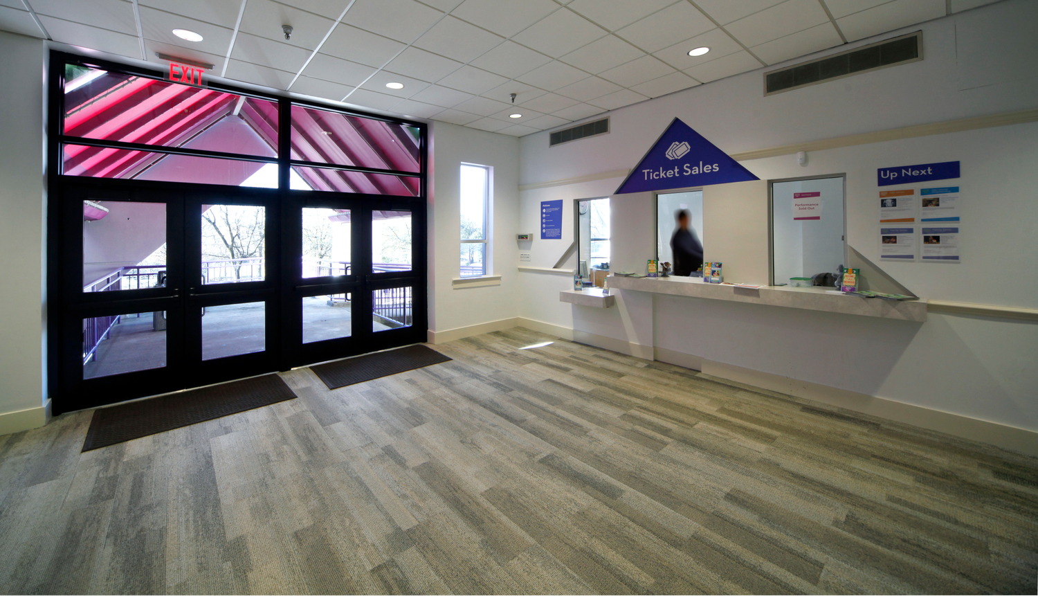 12882_00_Center_for_Puppetry_Arts_N73_HumanityEdit1 Bright, spacious lobby of the Center for Puppetry Arts featuring large glass exit doors on the left and a ticket sales counter on the right. A calm, welcoming atmosphere.