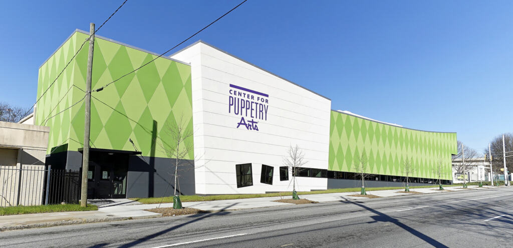 Modern building of the Center for Puppetry Arts featuring a vibrant façade with green diamond patterns and large sign on a sunny day.