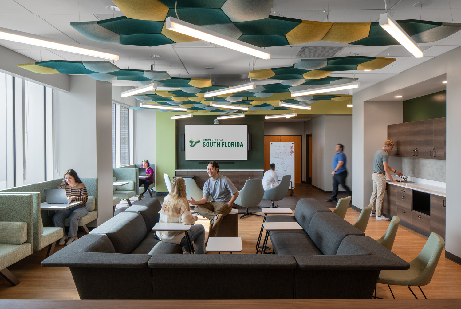 R24_16126_00_USF_ISA_Lab_N11_medium Modern lounge area at University of South Florida, featuring people chatting, working on laptops, and a vibrant ceiling design, creating a collaborative atmosphere at ISA Biomedical Labs