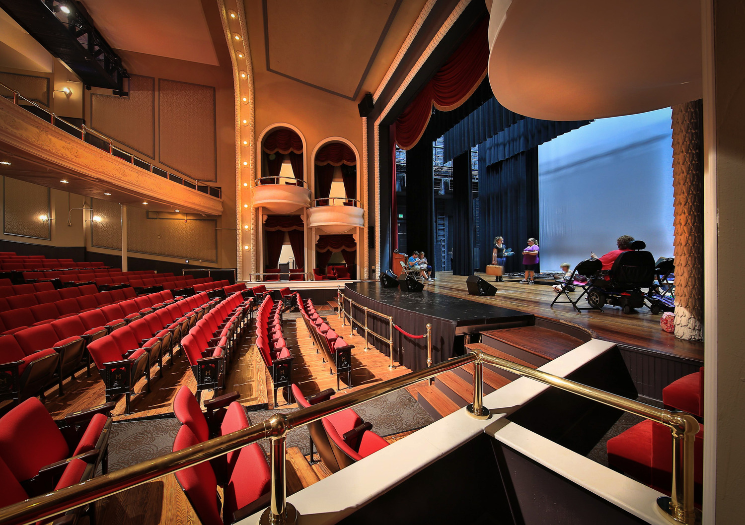 Theatre rehabilitation at the Historic Masonic Theatre featuring ornate balconies, red auditorium seating, and a spacious stage during rehearsal.