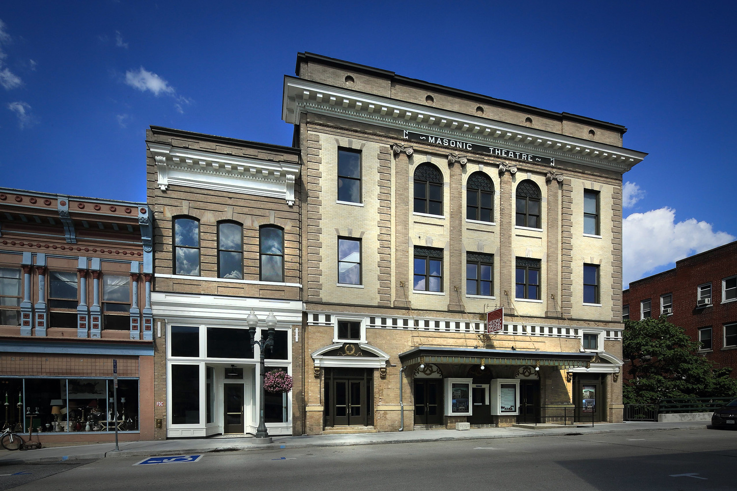 Historic Masonic Theatre with a classic facade featuring arched windows and ornate details under a blue sky. The scene exudes a timeless charm.