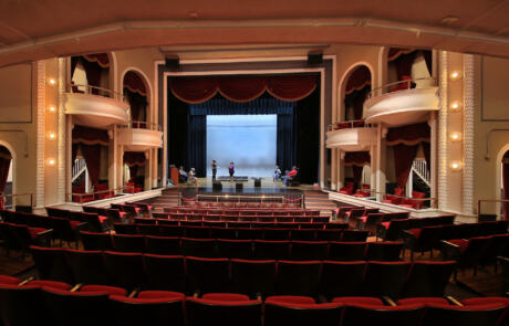 Theatre rehabilitation at the Historic Masonic Theatre featuring red velvet seating, ornate balconies, and a restored stage framed by classic curtains.