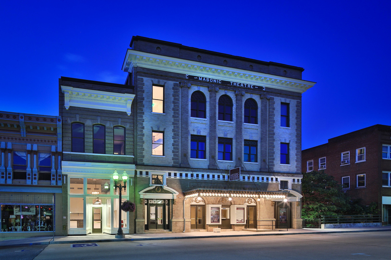 Historic Masonic Theatre illuminated against a deep blue sky, showcasing elegant architecture, arched windows, and a vintage marquee, evoking a sense of nostalgia.