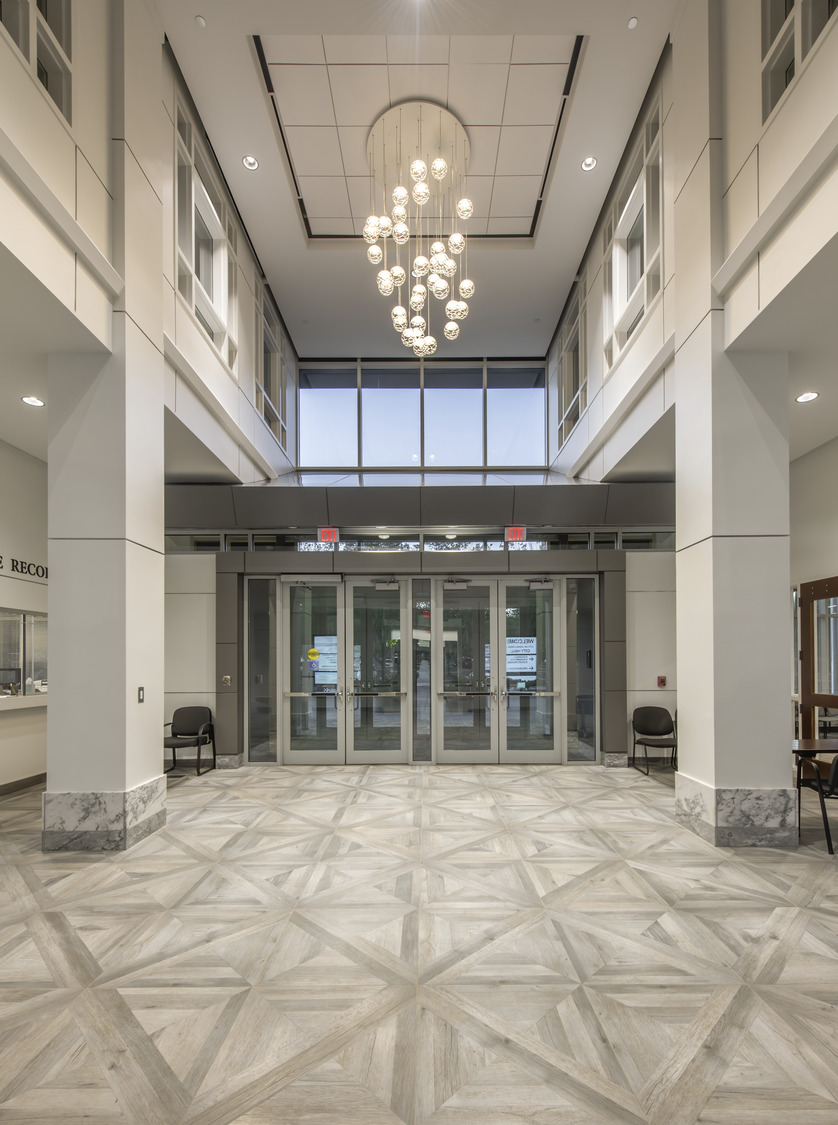 Neutral tones in a two-story entrance area with decorative light and large columns at the Johns Creek Municipal Center